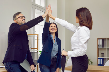 Happy successful business team giving high fives cheering their success. Professional business...