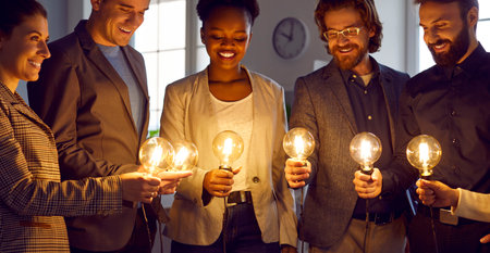 Business people look at bright idea light bulbs. Smart multiracial team share professional insights,...