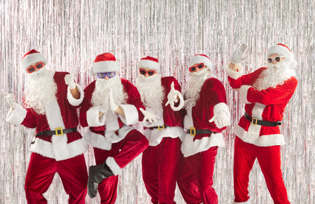 Portrait of a group of happy funny people in Santa Claus red costumes having fun celebrating New...