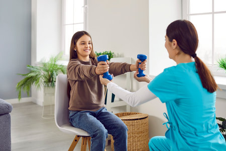 Happy child patient undergoing physiotherapy rehabilitation after injury. Smiling girl sitting on...