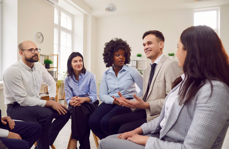 Young diverse business people in formal clothes discussing work project sitting on chairs in circle...