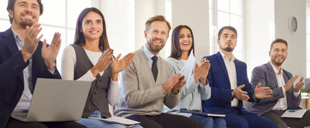 Smiling business team sitting in modern office, clapping and showing support and appreciation. Happy professionals applauding during corporate event, conference or successful presentation. Banner.の写真素材