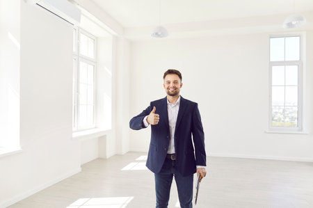 Portrait of a happy real estate agent or realtor giving a thumbs up in a new home or office. The agent smiles with confidence, showcasing success and satisfaction in the real estate industry.の写真素材
