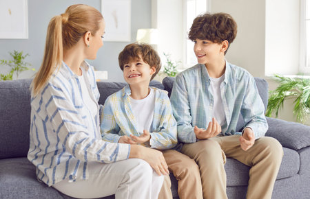 Loving mother, caring woman with little and teen son close, enjoy time together at home on weekend, children development, two generations family love, sitting on sofa, feel happy to show supportの写真素材