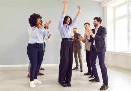 Happy funny positive diverse team of managers applauding coworker enjoying team success, office friendship, teamwork, successful entrepreneur, multiethnic colleagues celebrate business success, relaxの写真素材