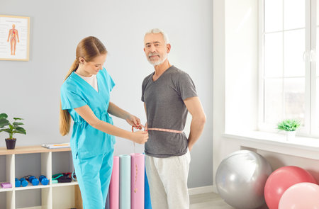 Female doctor, young nurse and senior old patient holding measurement tape to measure waist after...