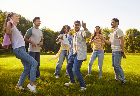 Portrait of a group of excited happy young people friends having fun hanging together in nature in...