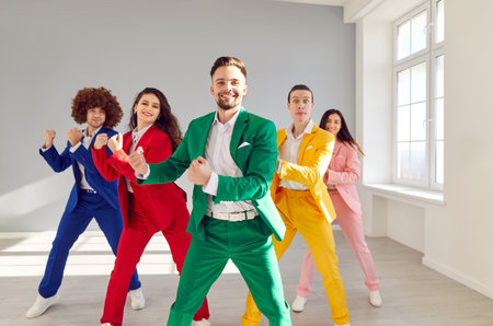 Funny dancing happy people group wearing bright vivid color formal suit dancing, funny disco, rock and roll lover dancers enjoy office party, overjoyed excited young team spending active free timeの写真素材
