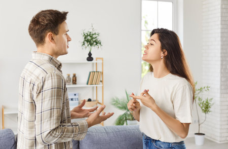 Young couple quarreling in the living room, close-up. An irritated wife reprimands her husband for his mistakes at home. Concept relationship problemsの写真素材