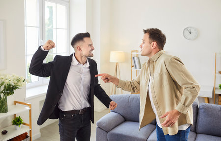 Two men are in a heated argument in a living room, with one man pointing and the other raising a...