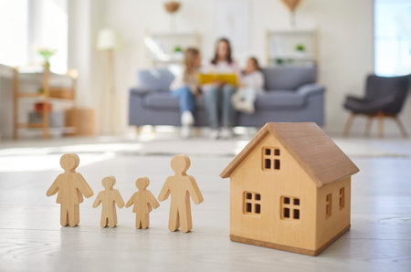 Real estate, wooden toy house dream, set of four wooden figures representing friendly family, new home, security, and togetherness, existing property owners in living room blurred scene backgroundの写真素材