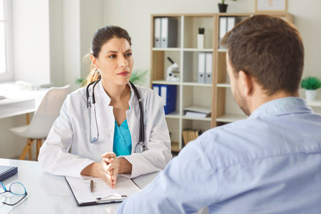Female doctor in white medical uniform consulting male patient, consultation in clinic, GP talking to discuss, checkup results with client at meeting in hospital, share treatment plan, therapistの写真素材