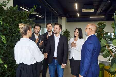 Business leader and woman shake hands in modern office, team of colleagues applauding handshake and greeting female professional. Welcome meeting and recognition in corporate companyの写真素材