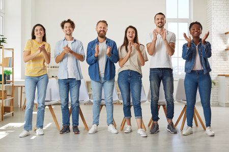 Friendly multiracial people in casual clothes stand in row and applaud looking at you. Group of...