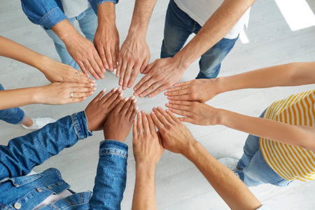 Team of young people joining their hands. Group of multiracial people in jeans and T shirts putting...