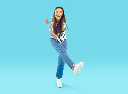 Full length portrait of funny crazy joyful brunette girl with long hair in striped blouse and jeans...