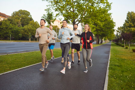 Team of athletes runs or jogs together outdoors during group training, boosting jogging effort,...