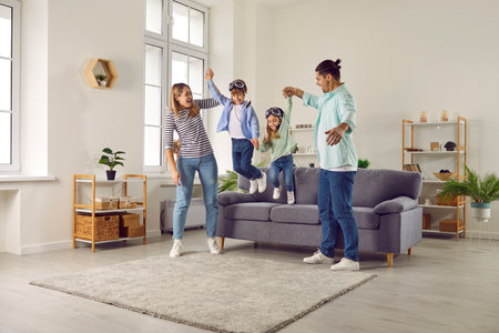 Happy smiling family having fun with their two kids boy and girl in the living room at home. Couple...