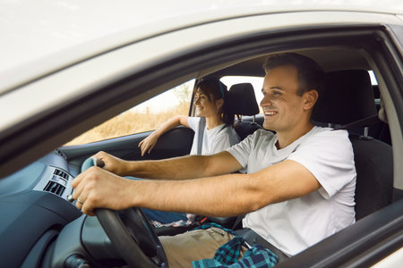 Couple in car on weekend roadtrip travel. Smiling driver and relaxed passenger enjoy rental driving...