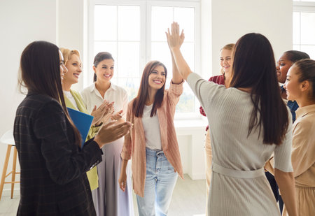 Happy multiracial female team standing in office, giving each other high five and applauding. Group...
