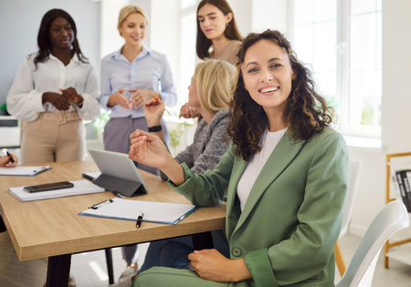 Woman portrait leads team meeting in office. A diverse group collaborates, planning strategy and training goals, building leadership and teamwork. Concept: women leadership strategy teamwork.の写真素材