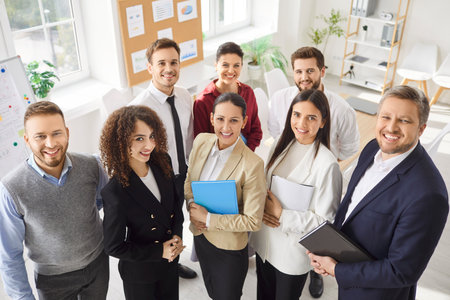 Diverse and positive business people group poses for a team portrait in an professional office setting. Teamwork, community, and collaboration among professionals engaged in work activities.の写真素材