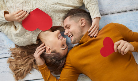 Happy beautiful young couple having fun on Saint Valentines Day. Man and woman in love lying on...