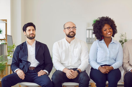 Multicultural group of happy business people sitting in a row, close-up. Interracial team in training, briefing in the company. Concept executive staff, employee engagement, business meetingの写真素材