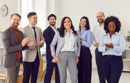 Interracial happy team clapping hands for young business woman, close-up. Multicultural group of business people greeting a colleague. Concept business lifestyle, employees togetherの写真素材