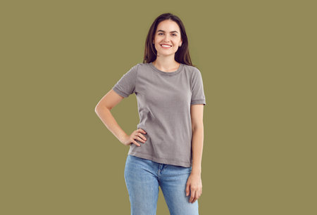 Portrait of a happy, smiling, young brunette dressed in a T-shirt and blue jeans, looking at the...
