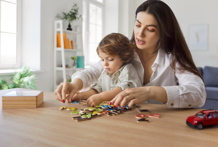 Mother and toddler little kid learning with play at home. Parent woman playing developing game with child learning alphabet sitting at table. Family leisure, education and bonding concept.の写真素材