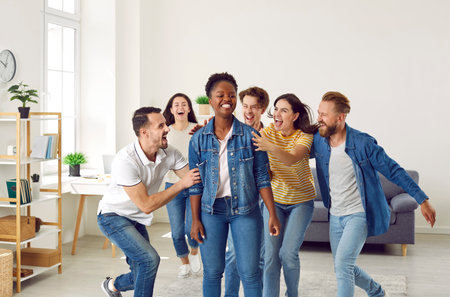 Joyful diverse friends having fun together. Group of excited people congratulating their friend on...