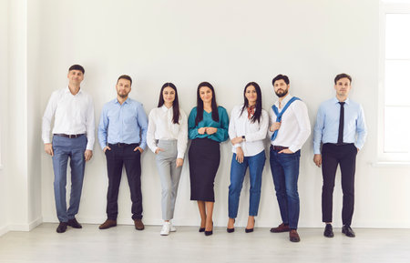 Full length portrait of confident business people in formal clothes looking at camera and smiling indoors. Group of staff standing in office. Business people portrait.の写真素材