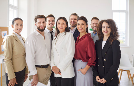 Diverse team portrait of happy business employees meeting in office, standing looking at camera, smiling, laughing, celebrating success, leader, boss, posing with working group, hr welcomingの写真素材