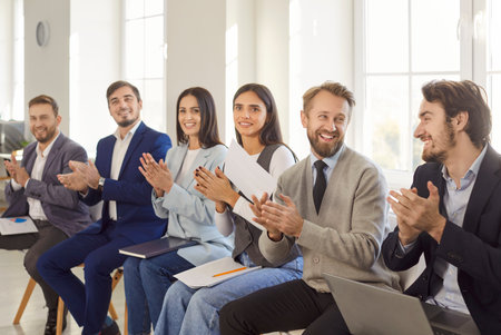 Group of a positive and diverse business people applauding and celebrating success during a meeting...