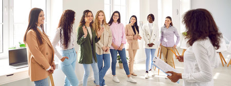 Smiling motivated female participants talking together at corporate meeting, staff training. Speaker...