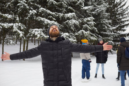 Portrait of smiling happy man in winterwear enjoying snowy winter on holidays or vacation walking in...