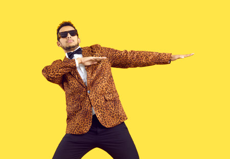 Portrait of a funny dancer. Studio shot of a young black man wearing a leopard party jacket, bowtie...