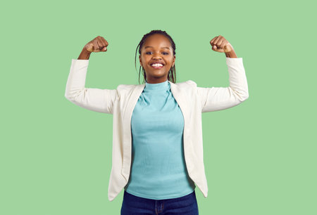 Young African woman demonstrates her strength. Happy active strong African American model standing...