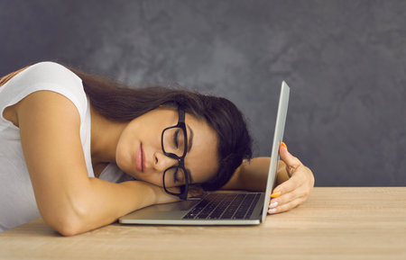 Exhausted woman in glasses, college girl, university student, programmer or web developer lying down...