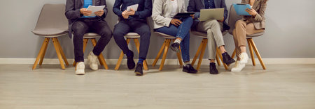 Legs of various people sitting in row in waiting room before interview or business meeting. People...