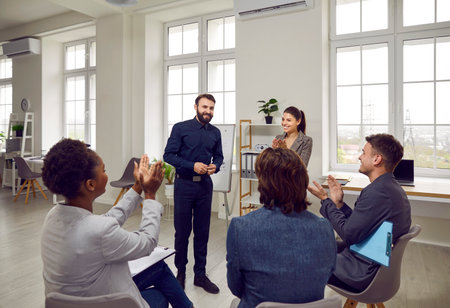 Team of happy diverse people applauding a business coach. Group of men and women meet in the office,...