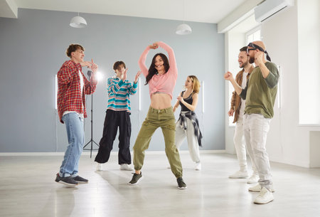 Active young people having dancing class lesson, moving energetically to music in dance hall....