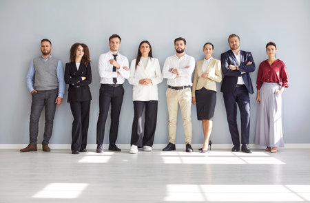 Group of confident business people men and women looking at camera and smiling on gray wall background. Company employees team or group of staff standing in office on formal clothes.の写真素材