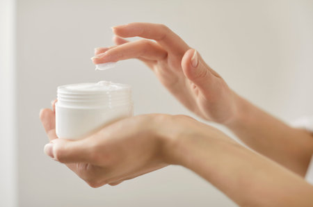 Close up of female hands holding cosmetic cream jar, lady trying moisturizing revitalizing creme lotion on finger for applying on hand, face, body skin to advertise skin care, beauty spa treatmentの写真素材