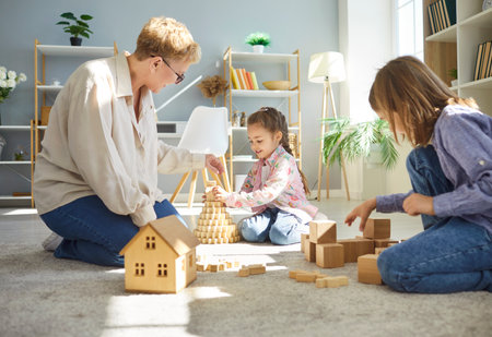 Happy family together, grandchildren and grandmother friendly playing toys at home, sit laughing on floor, love, warmth, care, enjoying family relations, communication and close care, daycare nannyの写真素材