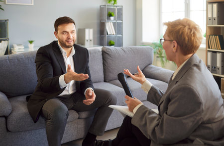 Businessman in interview speaks into microphone with journalist. He has focused conversation with...
