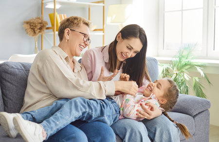 Happy family, grandmother, mother and child, sitting on sofa in modern living room, three...
