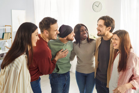 Happy people friends standing in circle and embracing, laughing and having fun, meeting together during weekend to celebrate something, dressed casually. Friendship and relationship conceptの写真素材