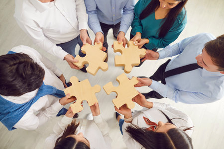 Close up shot of a group of business people hands working together to assemble wooden puzzle pieces. Symbolizes teamwork, collaboration, and effective communication within the company.の写真素材